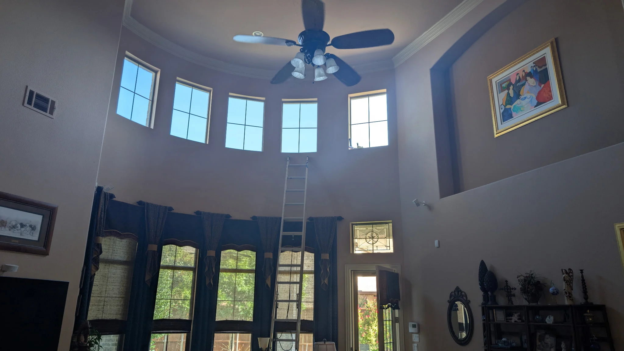 Upper windows above a McKinney living room, with a ladder in place for window-tint installation.